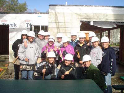 Member of the women's soccer team poses with their hammers and hard hats in front of the home they helped build last Sunday.